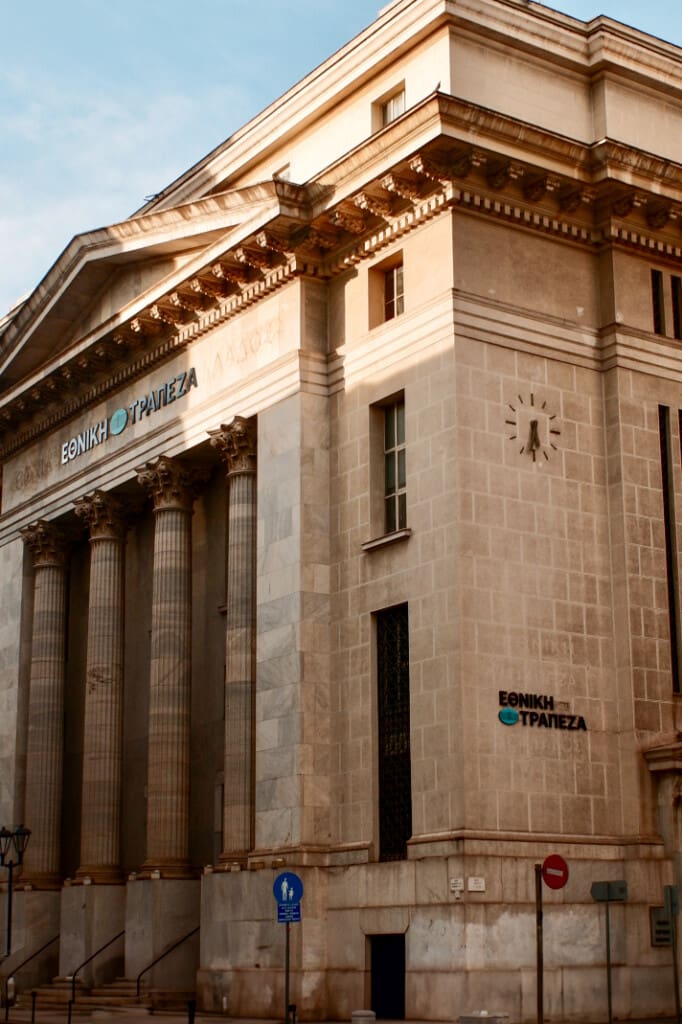 Back entrance of the National Bank of Greece with neoclassical columns and clock detail, located at Plateia Eleftherias Square in Thessaloniki.