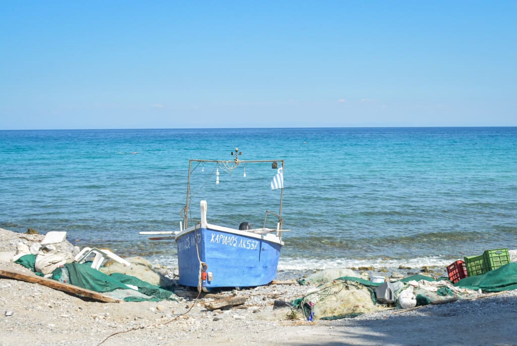 Small blue fishing boat with nets on the shore of the Olympian coast near Litochoro, Greece.