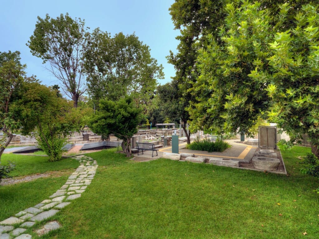 Outdoor exhibition garden of the Archaeological Museum of Thessaloniki with ancient stone monuments and lush greenery
